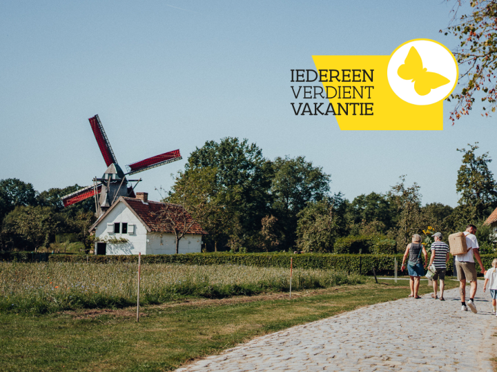 Gezin op wandel in het museum met op de achtergrond een windmolen en enkele andere historische gebouwen