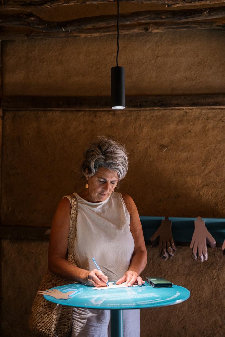 Vrouw schrijft boodschap op papieren handje in expo Moederziel