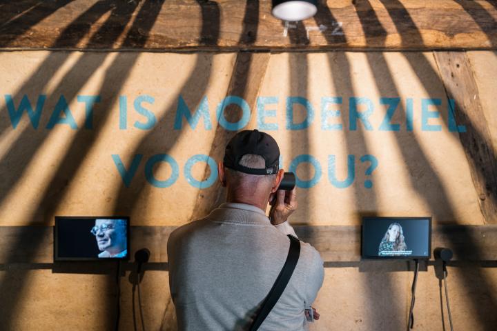 Man beluistert met luisterhoorn de fragmenten van experten in de expo Moederziel