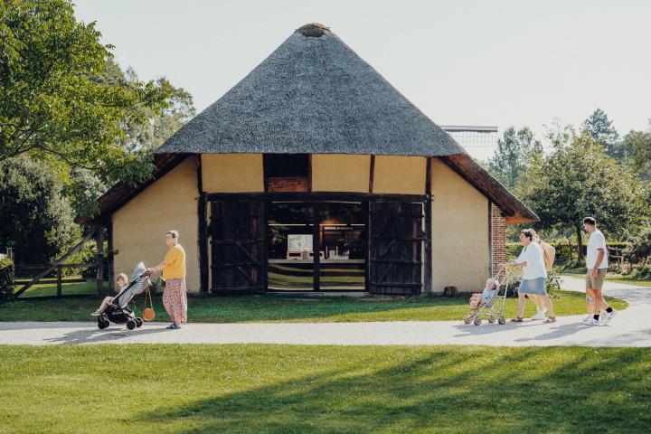 familie loopt met kinderen in buggy's langs een historische hoeve door