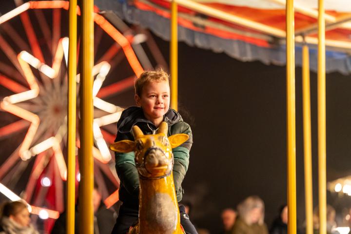 Jongetje zit op de nostalgische draaimolen tijdens Winterlicht