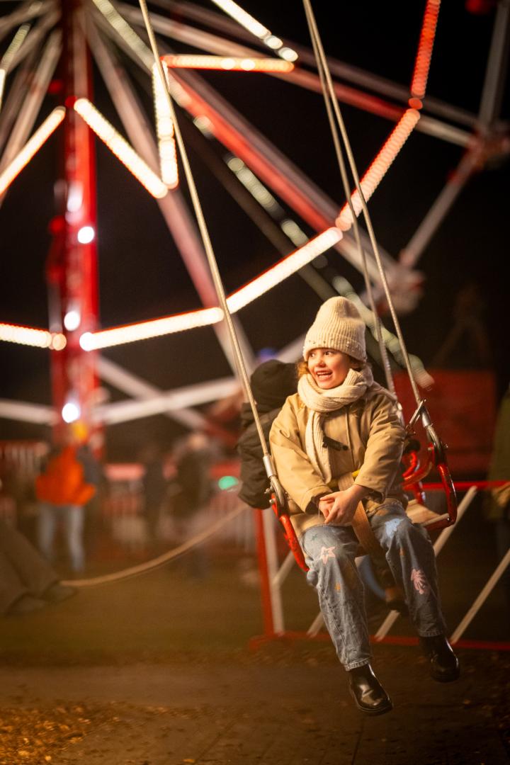 Meisje lacht op de zweefmolen tijdens Winterlicht