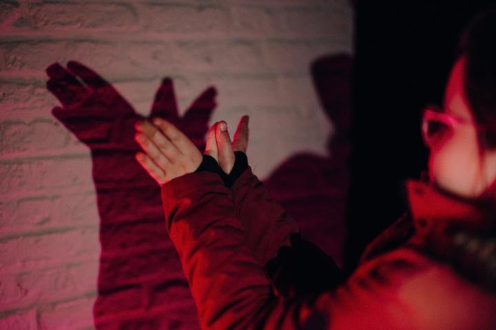 Meisje doet met haar handen schaduwspel op de muur van een verlicht historisch gebouw