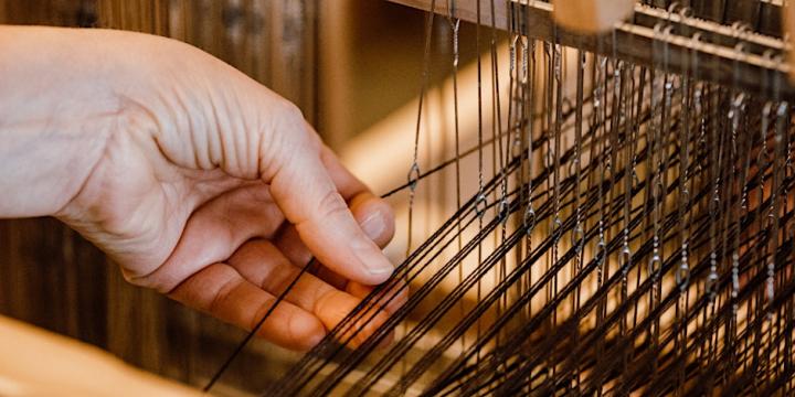 Iemands hand is aan het weven op een tafelweefgetouw