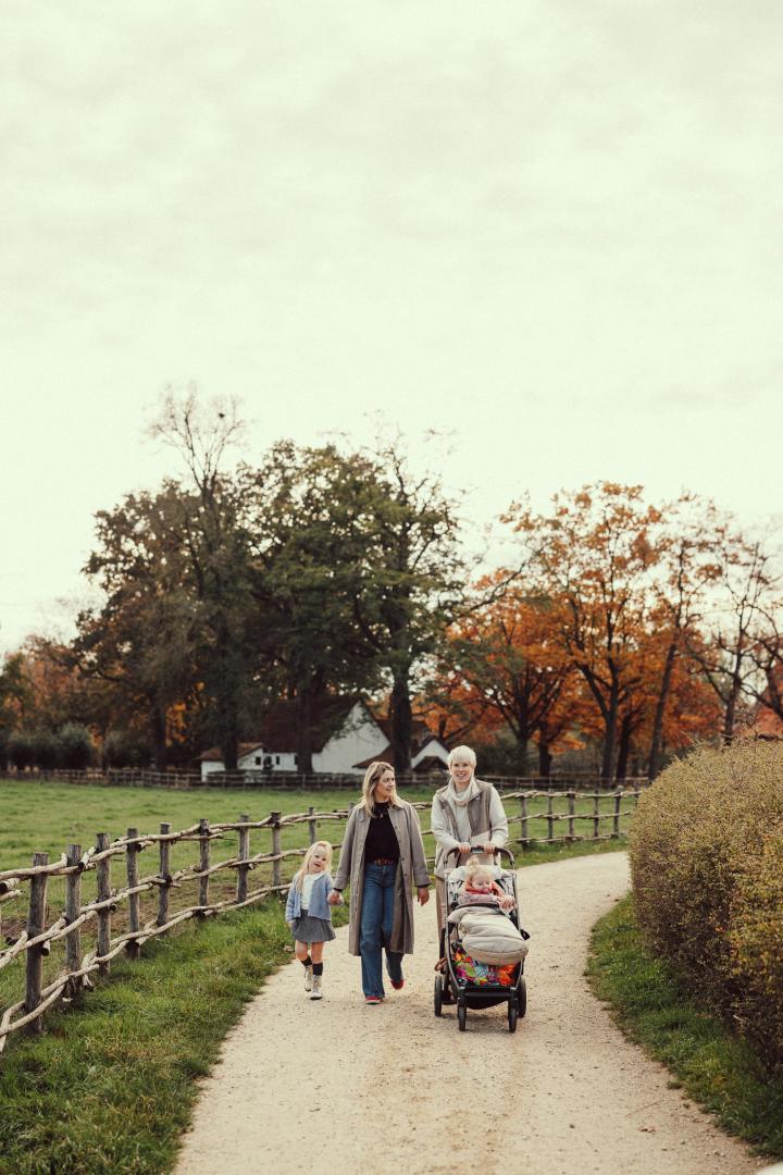Twee moeders maken samen met twee kinderen - waarvan eentje in een buggy - andeling in het museum in de herfst