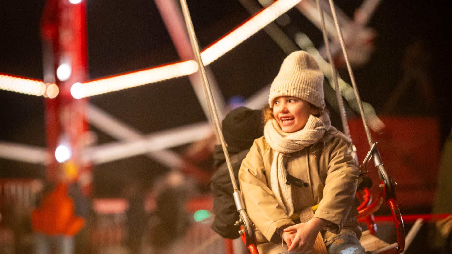 Meisje lacht op de zweefmolen tijdens Winterlicht