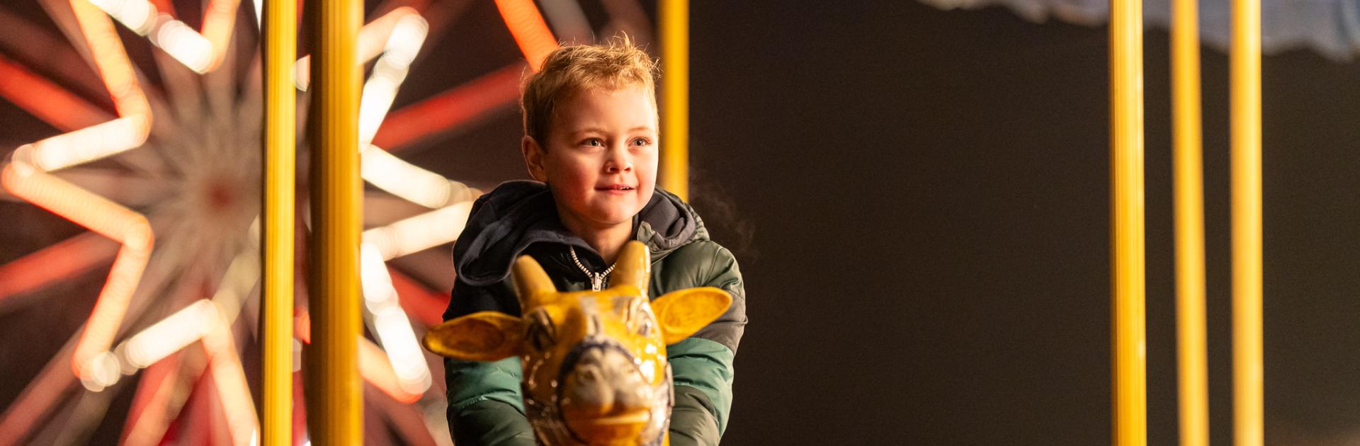 Jongetje zit op de nostalgische draaimolen tijdens Winterlicht