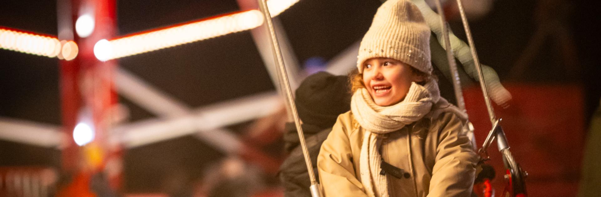 Meisje lacht op de zweefmolen tijdens Winterlicht
