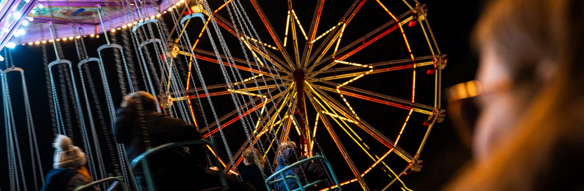 Verlicht reuzenrad en zweefmolen tijdens Winterlicht