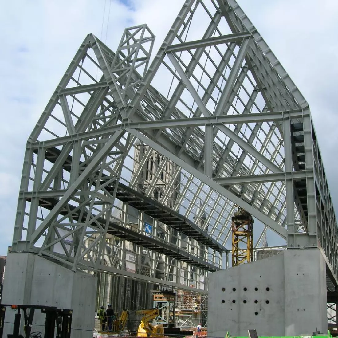 Vooraanzicht staalstructuur Kobra. De constructie rust op 4 betonnen sokkels. Achter de staalstructuur bevindt het Belfort van Gent.