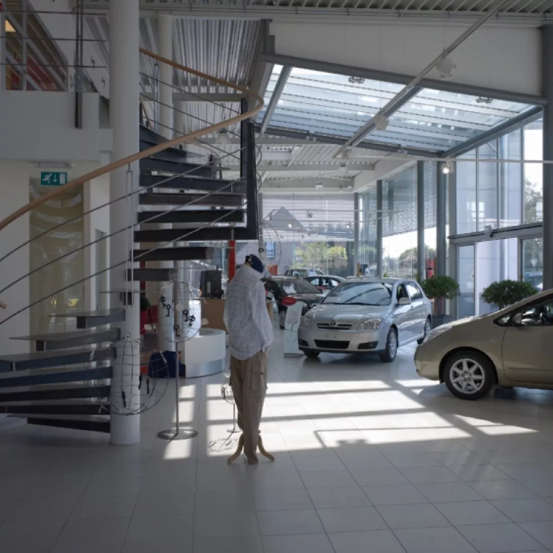 Binnenkant showroom garage Pieters. Er staan verschillende auto's binnen. Links bevindt zich een trap naar de volgende verdieping. Het is een wenteltrap.