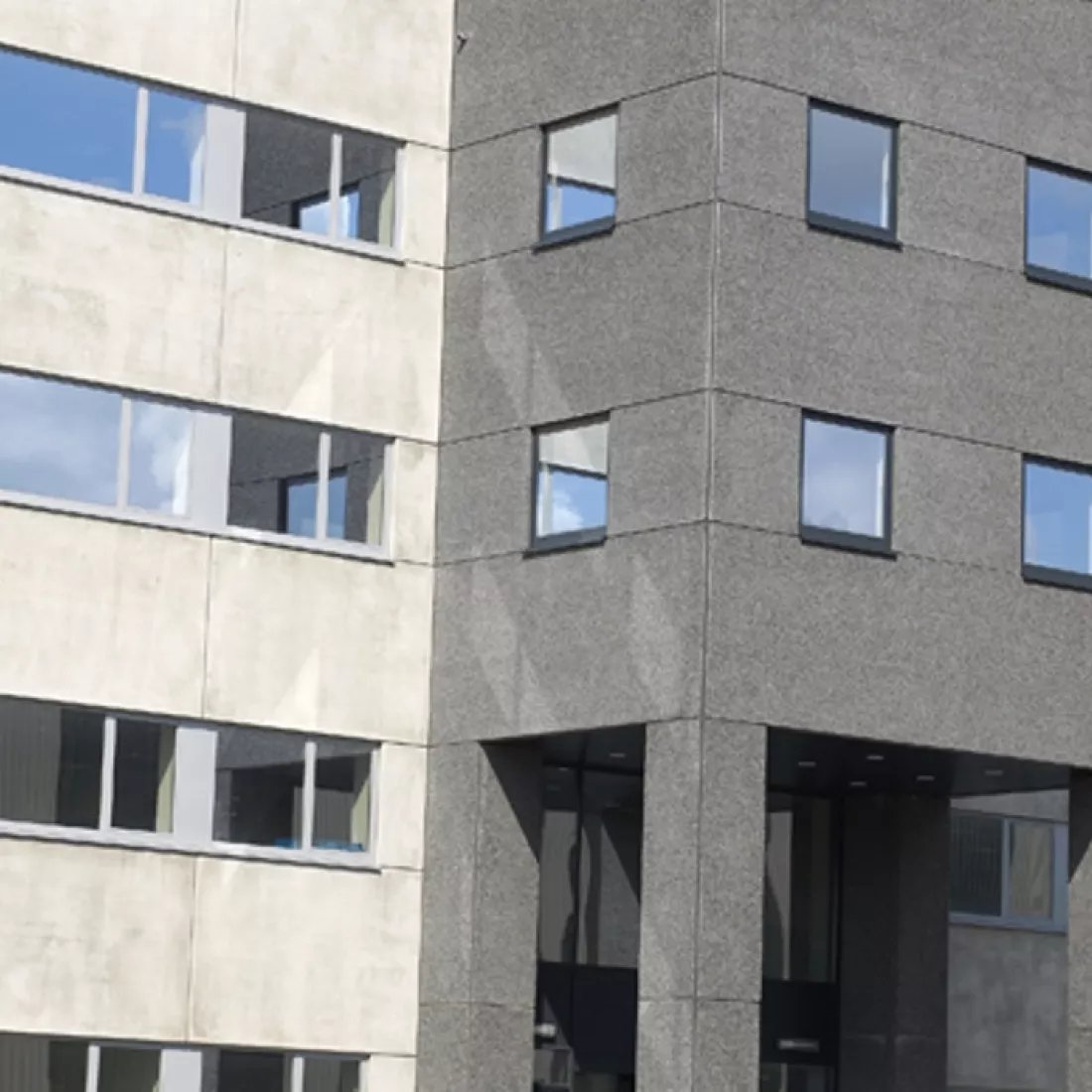  Close-up kantoorgebouw Nova Natie HQ. Het gebouw grijs. Er zijn veel ramen. Bij de opbouw werd er staal gebruikt.