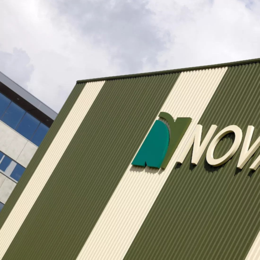 Close-up kantoorgebouw Nova Natie HQ. Dit gebouw is wit met groen.