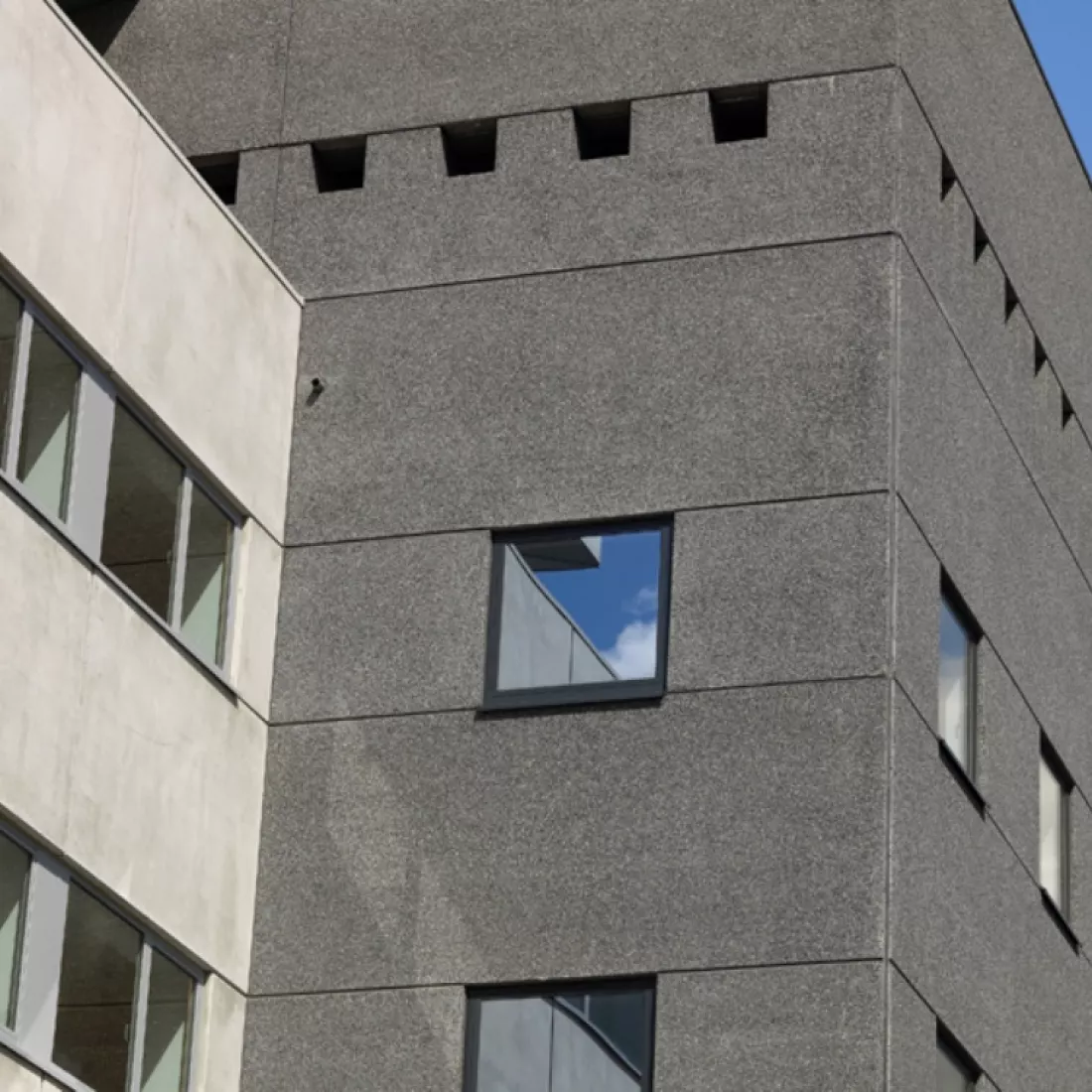 Close-up kantoorgebouw Nova Natie HQ. Het gebouw is grijs en bevat veel ramen.