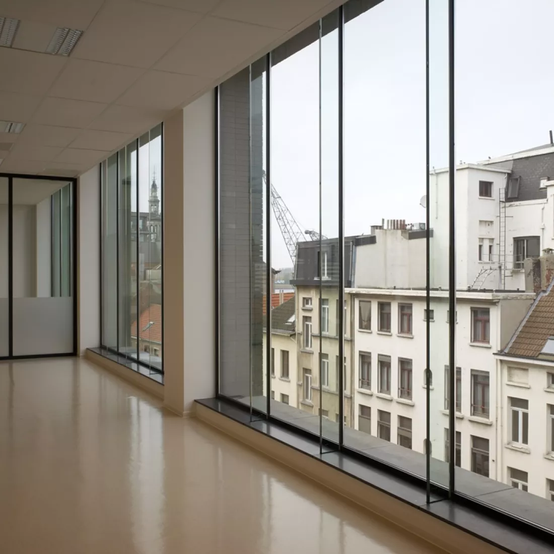 Binnenkant kantoor Cepa. Rechts bevinden zich grote ramen. Achteraan bevindt zich een glazenmuur. Het plafond, de muren en vloer zijn wit.
