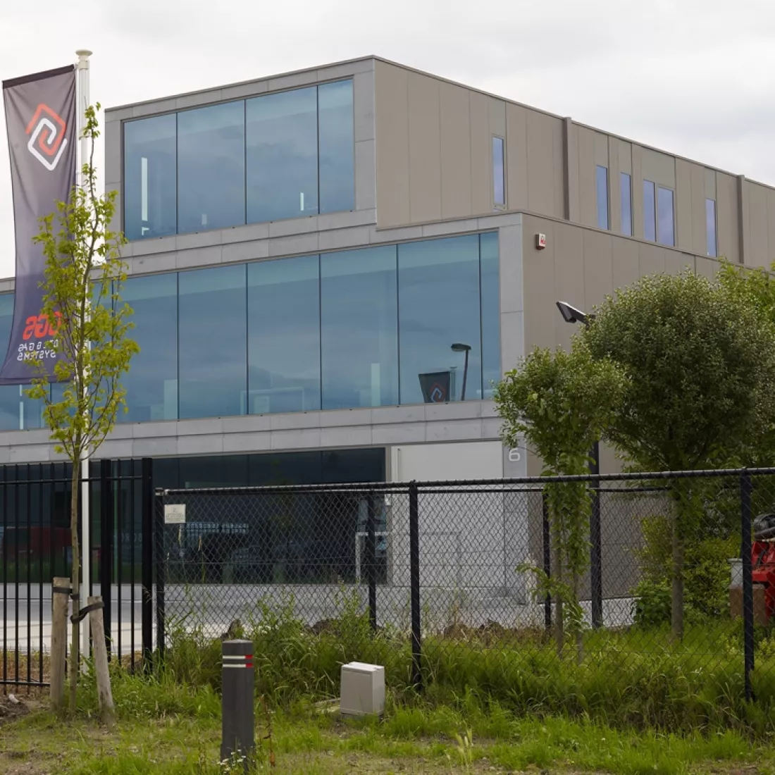 Zijaanzicht kantoor Global Gas Solutions. Het kantoor bestaat uit drie verdiepingen. De bovenste verdieping is kleiner. Elke verdieping heeft aan de voorkant grote ramen en aan de zijkant minder en kleinere ramen. rond het gebouw staat een zwart hek.