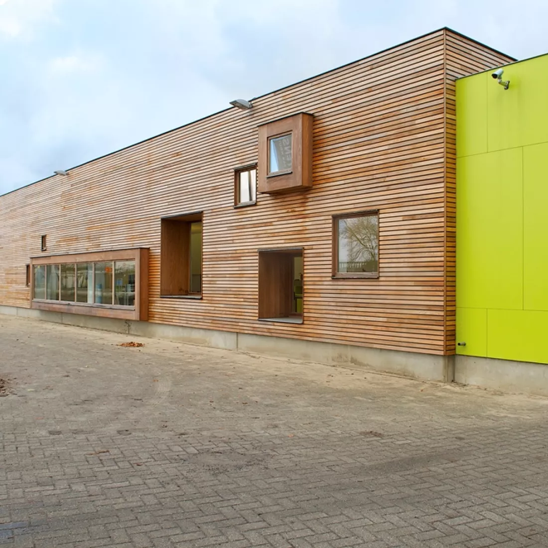 Toonzaal Martens Hout. Rechts bestaat het gebouw uit platen in de kleur van het logo en links bestaat het uit hout.