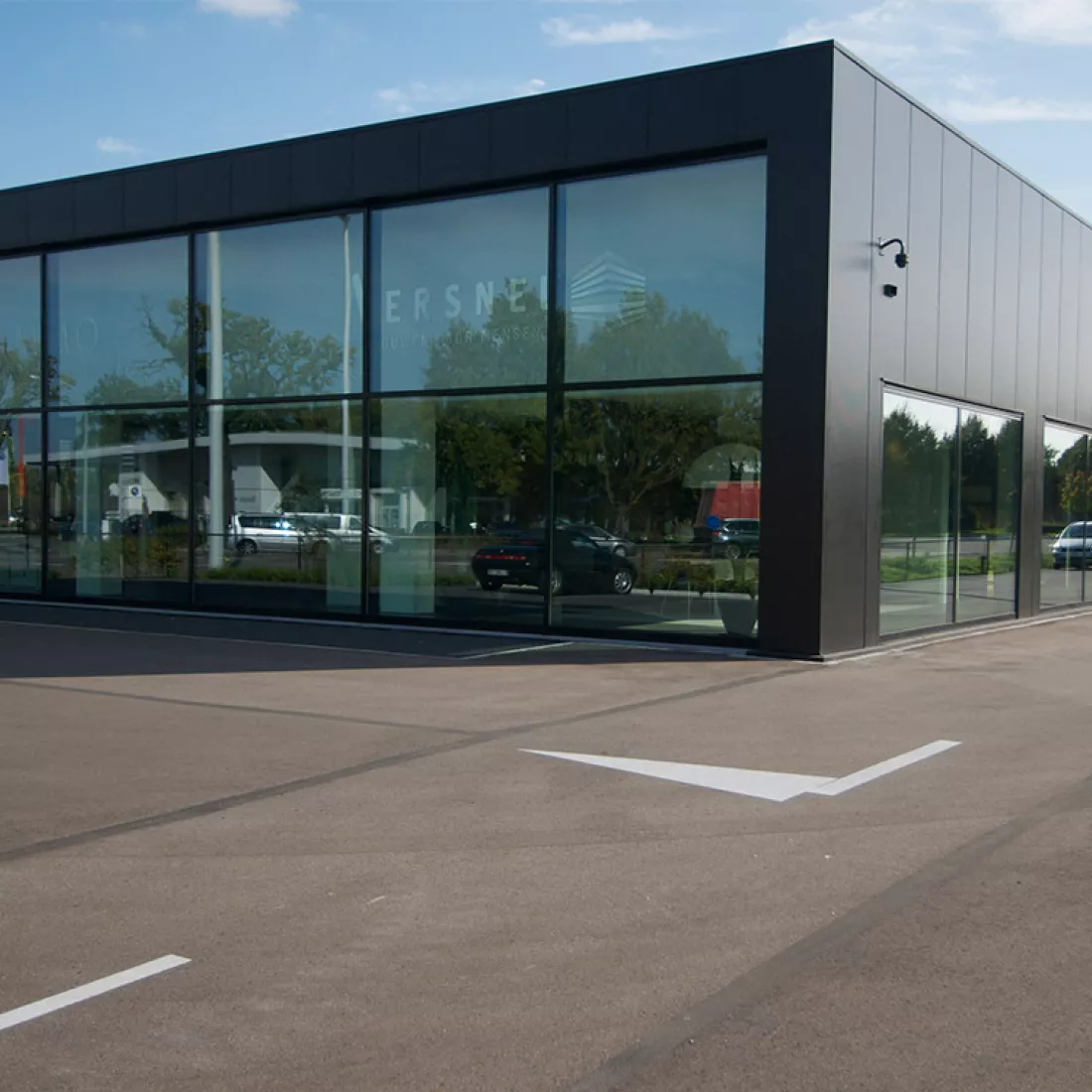 Zijaanzicht showroom Vimmo. Het gebouw is zwart en bevat veel grote ramen.
