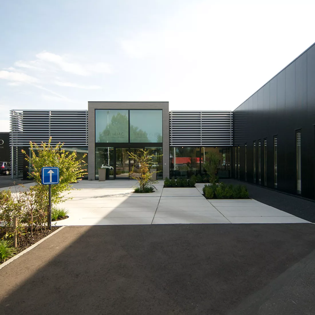 Vooraanzicht showroom Vimmo. Het gebouw is zwart met grijs en heeft veel ramen. Bij de opbouw is er staal gebruikt.