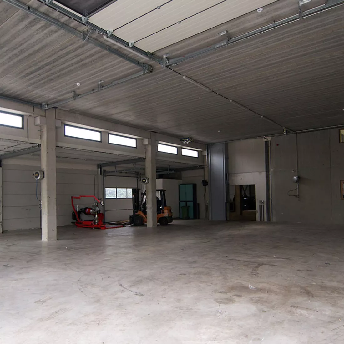  Binnenkant opslaghal banden - TSC. De binnenkant van de hal is nog leeg en bestaat uit beton. De hal bevat ook enkele kleine ramen.