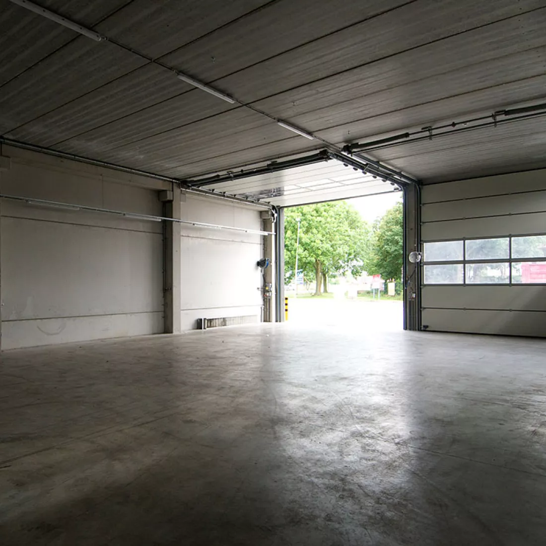  Binnenkant opslaghal banden - TSC. De hal is nog leeg en bestaat uit beton. Het gebouw bevat twee poorten naast elkaar.