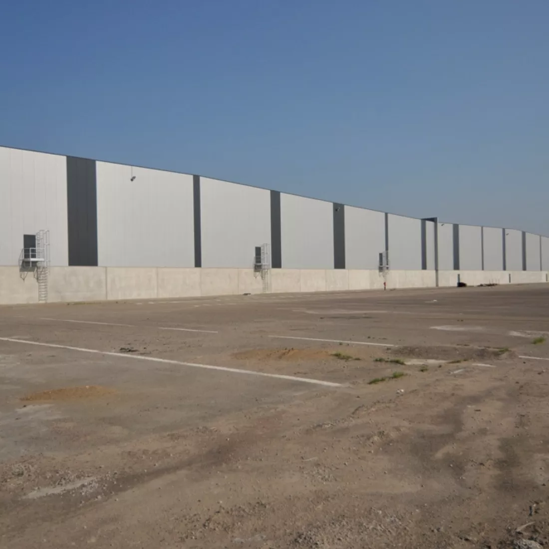 Buitenkant opslagplaats Scheldennatie. De opslagplaats is opgebouwd met een combinatie van verschillende materialen. Het gebouw bestaat uit lichtgrijze en donkergrijze platen.