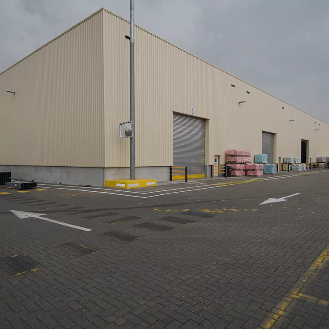 Buitenkant magazijn Saint Gobain. Het magazijn bevat drie grijze poorten.