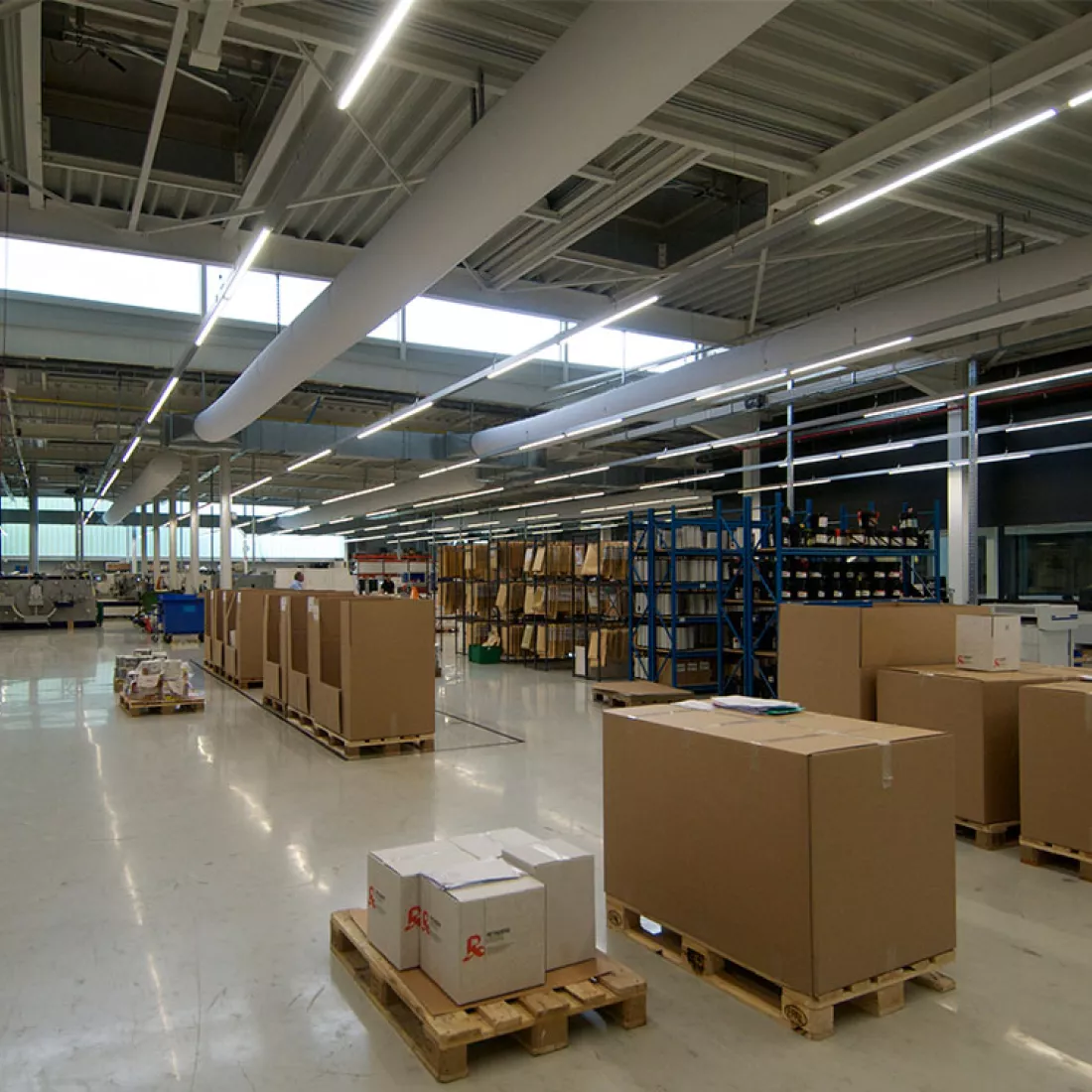 Binnenkant productiehal - Reynesco. Er staan verschillende materialen opgeslagen. Rechts staan materialen in rekken.