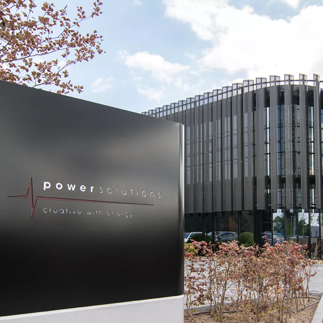 Zijaanzicht KMO gebouw met loods en kantoren van Power Solutions. Het gebouw is zwart en bevat veel ramen.