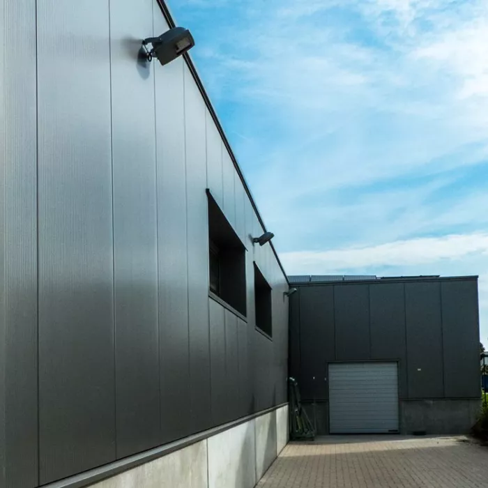 Zijaanzicht renovatie bedrijfsgebouw Palethoeve. Het gebouw heeft zwarte wanden en een grijze poort. Tijdens de opbouw is staal gebruikt.