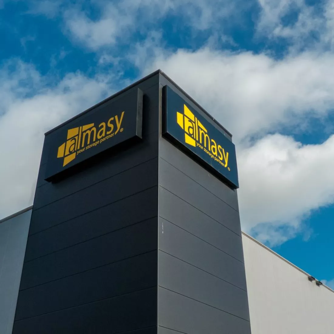 Onderaanzicht industriehal Almasy. De hal is grijs met zwart. Het logo van Almasy hangt ook tegen de hal.