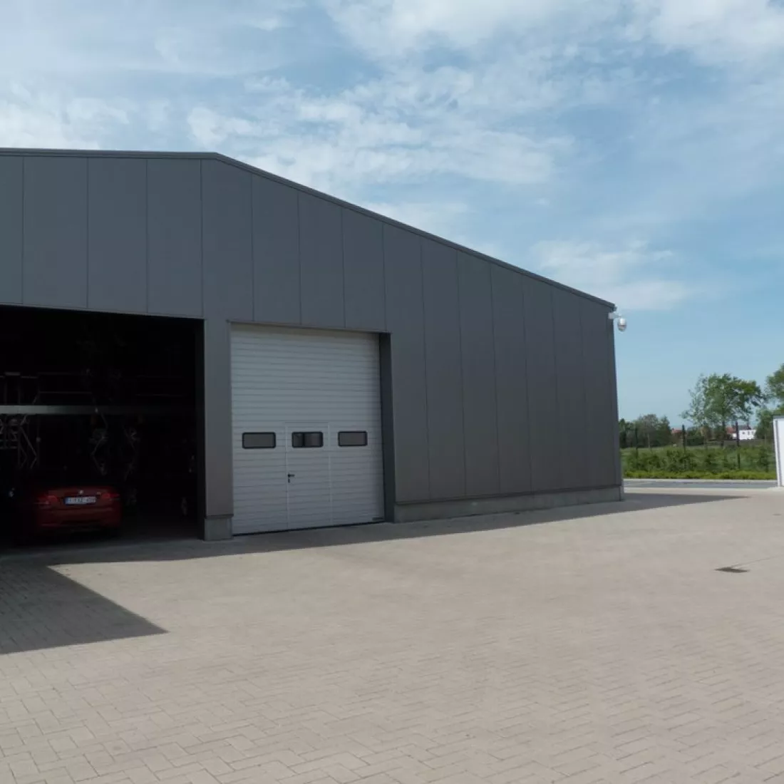 Vooraanzicht bandenloods garage Meeusen. Het gebouw is zwart en opgebouwd met staal.