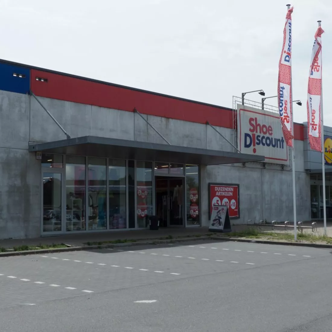 KMO Units Picolo - Van Ende: Shoe Discount. Tijdens de opbouw zijn er verschillende materialen gebruikt zoals beton. Naast de inkom hangt in het groot het logo van Shoe Discount. Links van de winkel bevindt zich de Hubo en rechts de Lidl. 