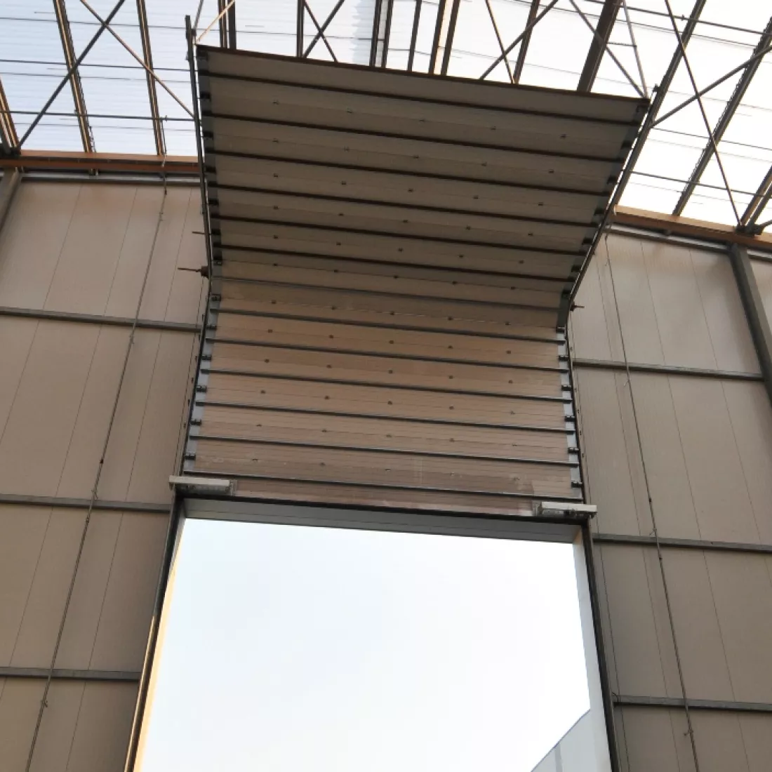 Binnenkant opslagplaats Scheldenatie. De afbeelding is een close-up van een poort die open is. Het plafond bestaat uit lichtstraten.