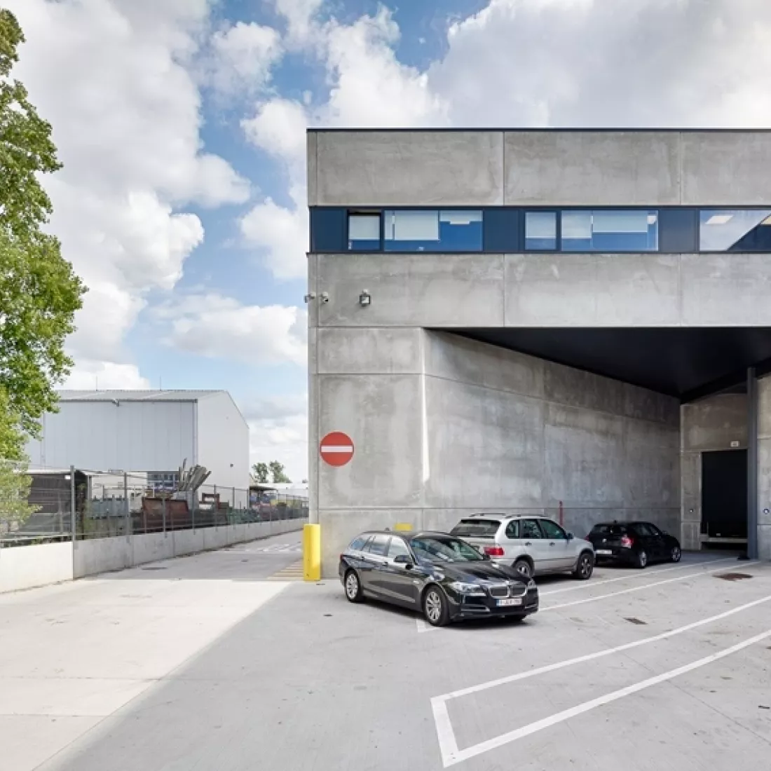 Buitenkant kantoor Transuniverse. De buitenkant is gemaakt uit beton. Bovenaan zijn er smalle liggende ramen.