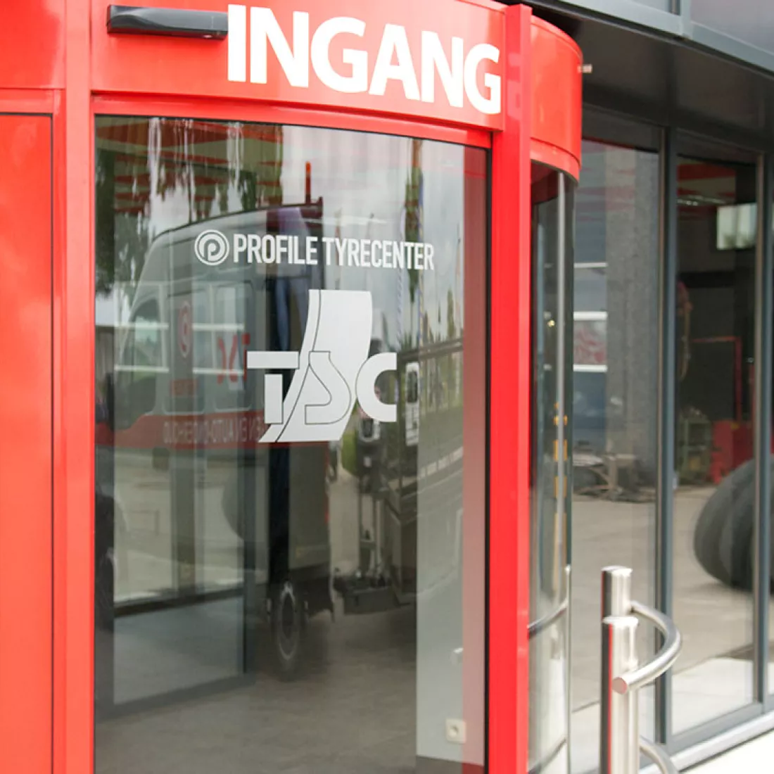 Ingang - TSC. De inkom bestaat uit een rode draaideur. 