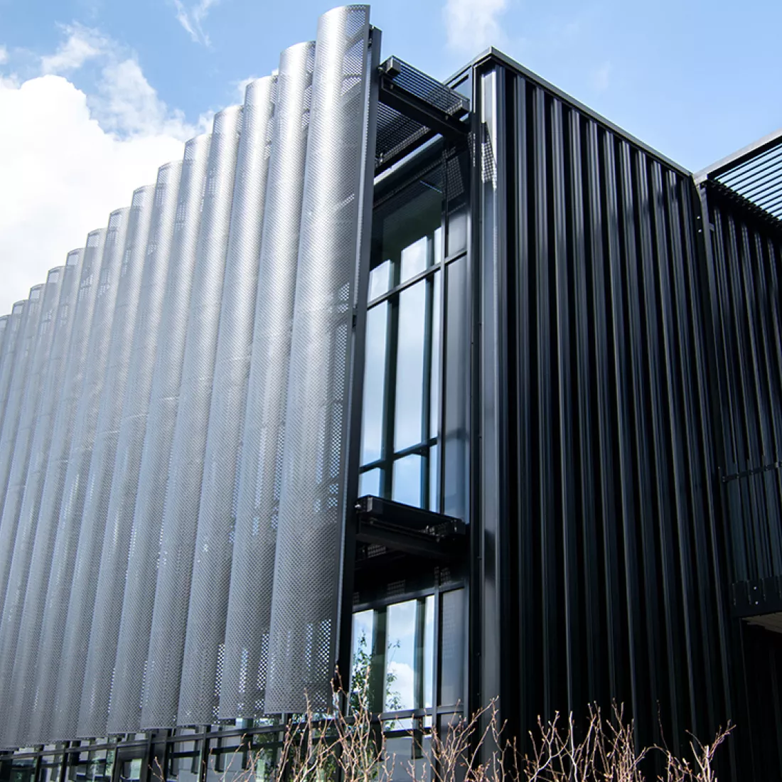Close-up buitenkant KMO gebouw met loods en kantoren van Power Solutions. Het gebouw is zwart en heeft twee verdiepingen. Het is gemaakt uit staal.