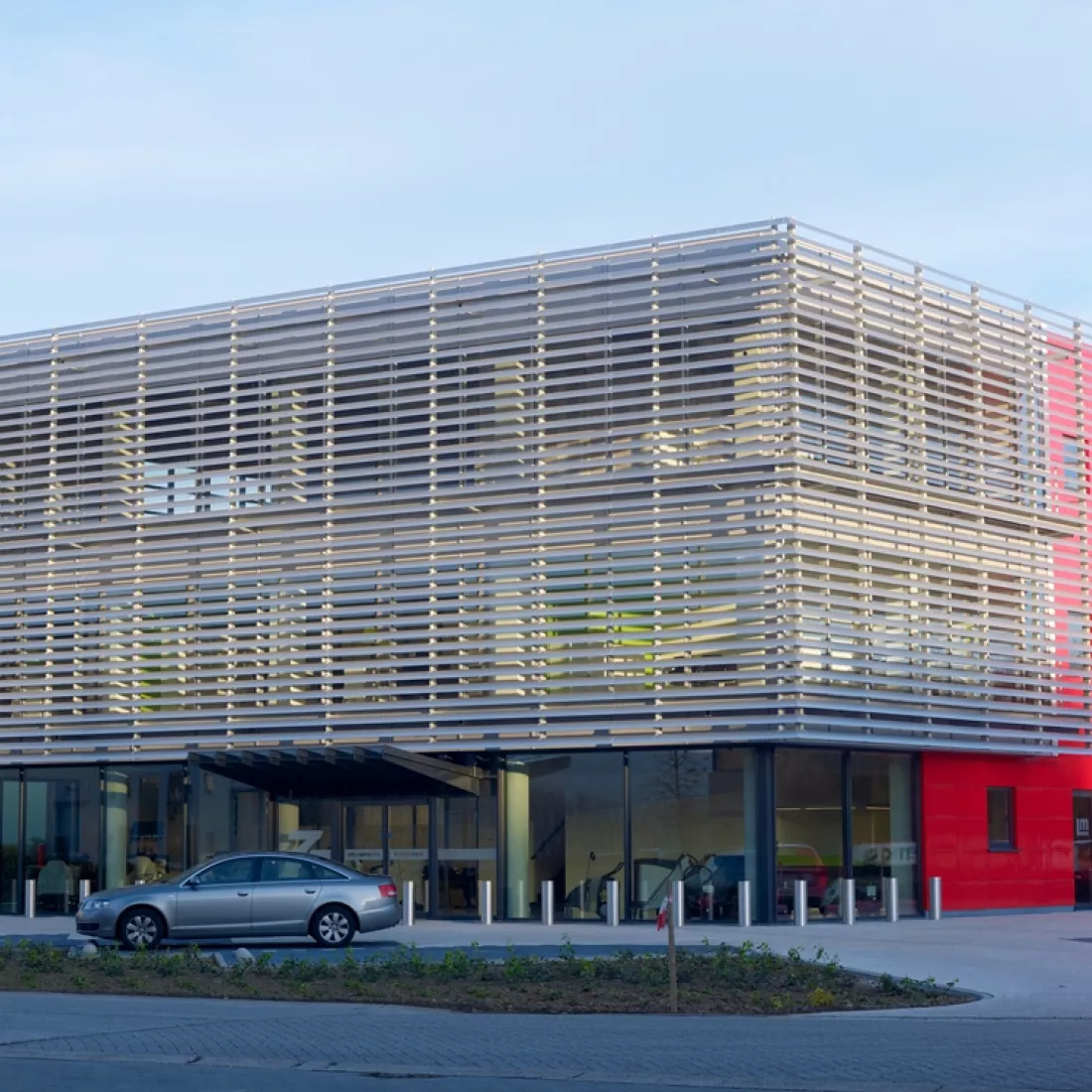 Vooraanzicht bedrijfspand met kantoor - DIBO Cleaning Systems. Het gebouw is opgebouwd met een combinatie van materialen. Het bestaat uit drie verdiepingen en bevat veel grote ramen. Voor het gebouw is een parking voorzien.