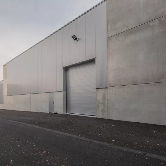 Buitenkant magazijn Corpack. Het is een grijs gebouw met een grijze deur en poort.