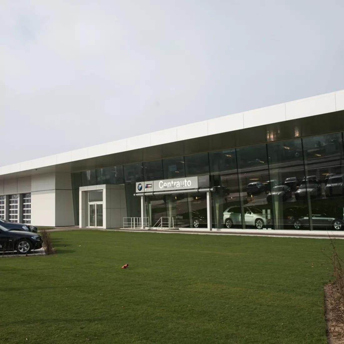 Vooraanzicht Centrauto. Voor het gebouw bevindt zich een grasveld. Rechts bevindt zich de showroom en links de garage.