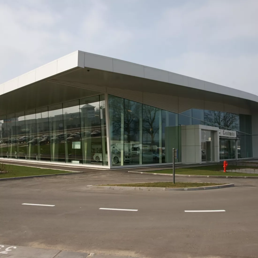 Zijaanzicht showroom Centrauto. Het gebouw bevat grote ramen. Rechts bevindt zich een inkomdeur.