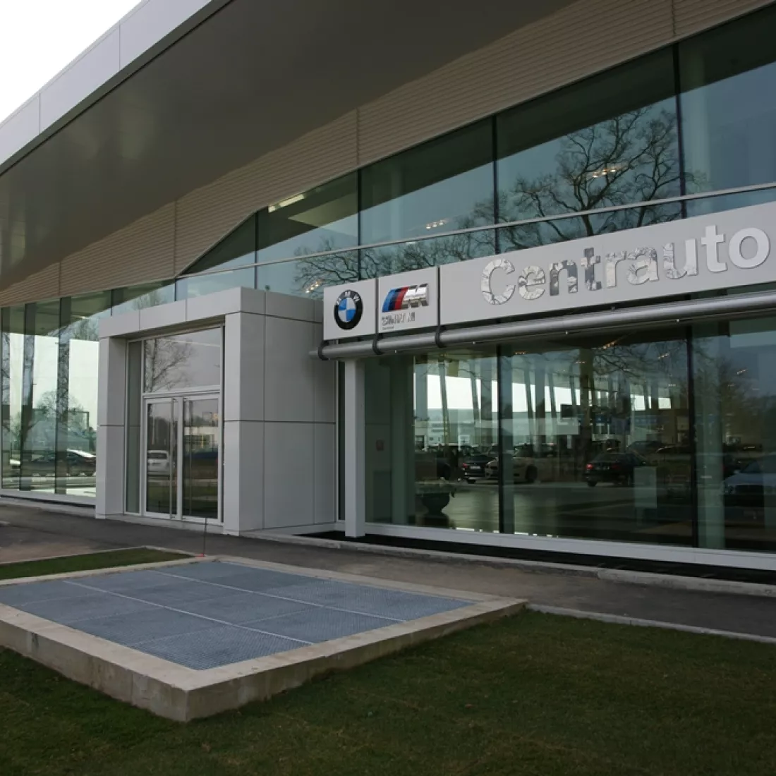 Close-up inkom showroom Centrauto. Rechts naast de deur hangt het logo van Centrauto.