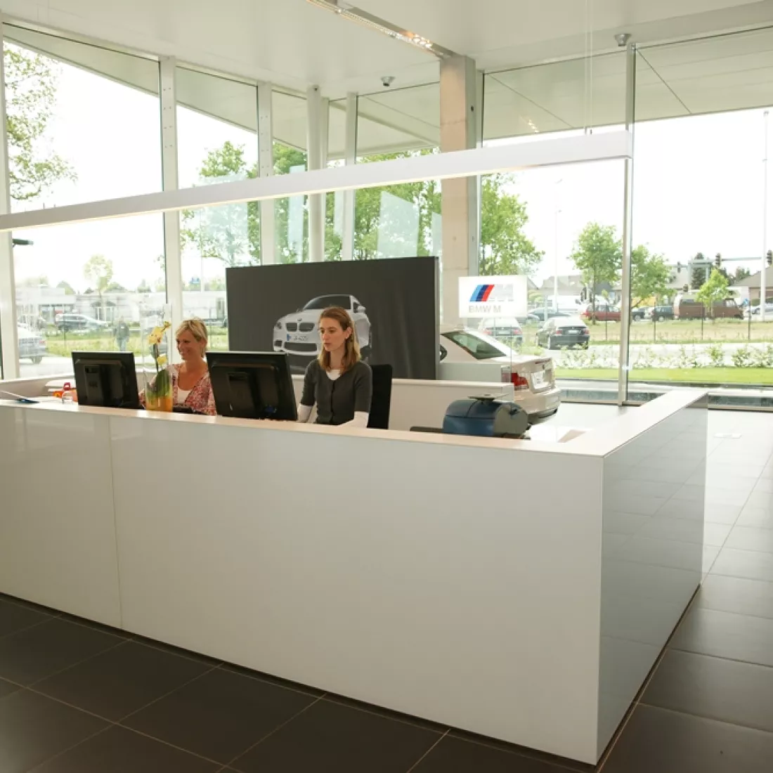 Onthaalbalie showroom Centrauto. De balie is helemaal wit. Achter de balie staat een auto tentoongesteld.
