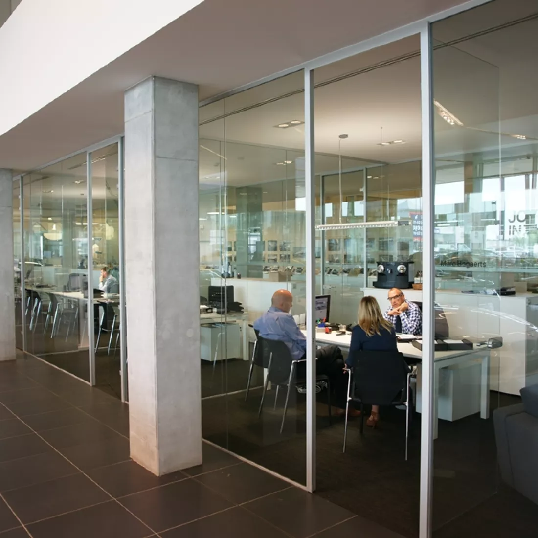 Binnenkant Centrauto - kantoren. De kantoren worden van elkaar gescheiden met glazenwanden.