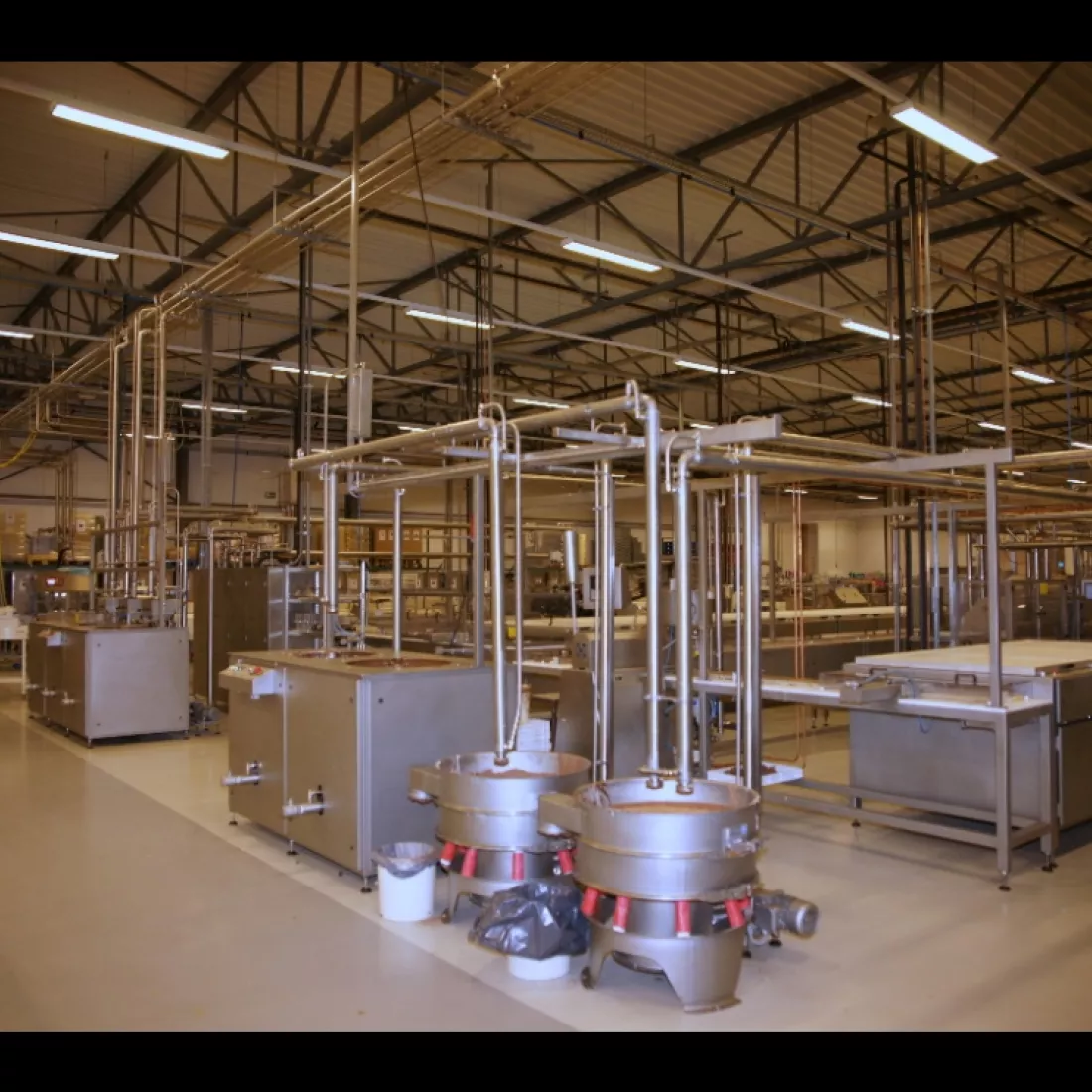 Binnenkant productieruimte Limar. De ruimte is gemaakt uit staal. Er staan veel productiematerialen. De foto is genomen vanuit zijaanzicht.