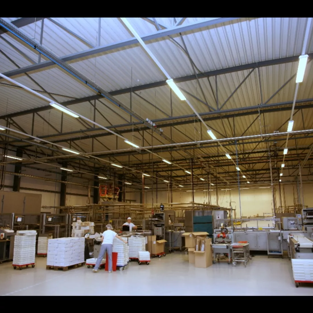 Binnenkant productieruimte Limar. De ruimte is gemaakt uit staal. Er zijn mensen aan het werk en er staan veel productiematerialen.