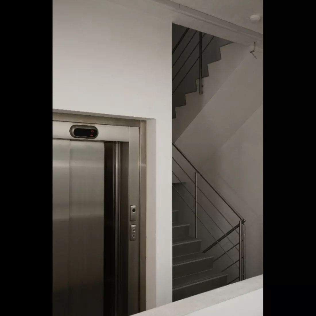 Trappenhal in het kantoor van Limar. Er is ook een lift aanwezig. De muren zijn wit.