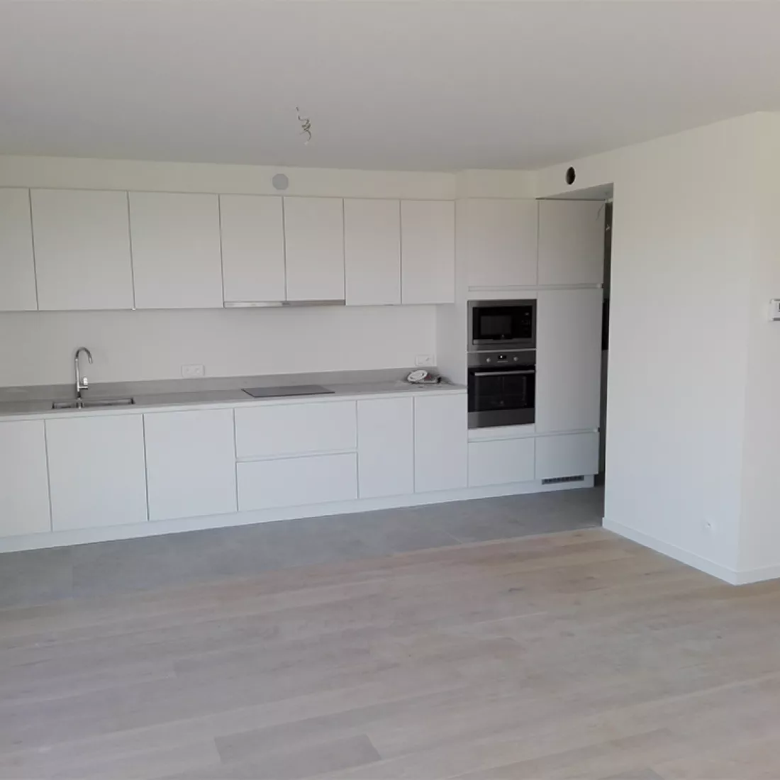 Binnenkant appartement Duin & Water shops. Binnenkant appartement Duin & Water shops. Het is een afbeelding van de keuken in het appartement. De keuken is volledig wit.