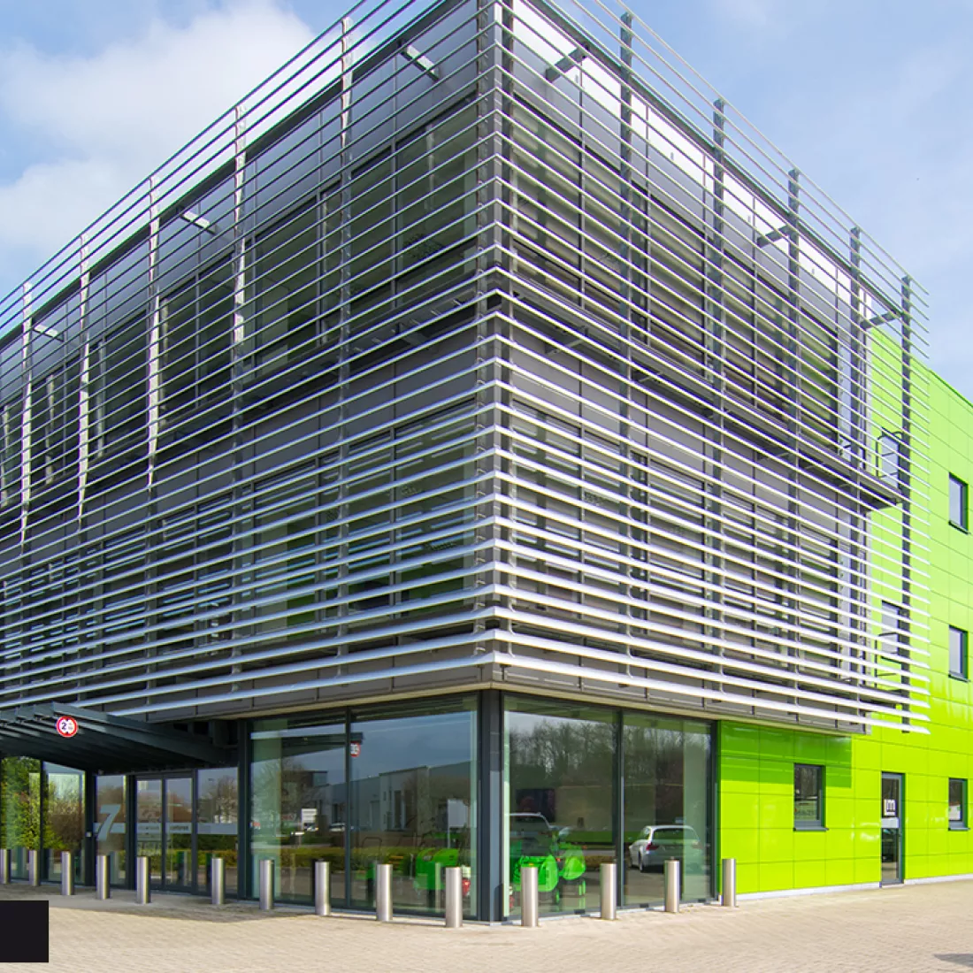 Zijaanzicht werkgebouw DIBO met groene tegels. Het gebouw bevat links en dus aan de voorkant grote ramen. Rechts bevat het gebouw groene tegels.