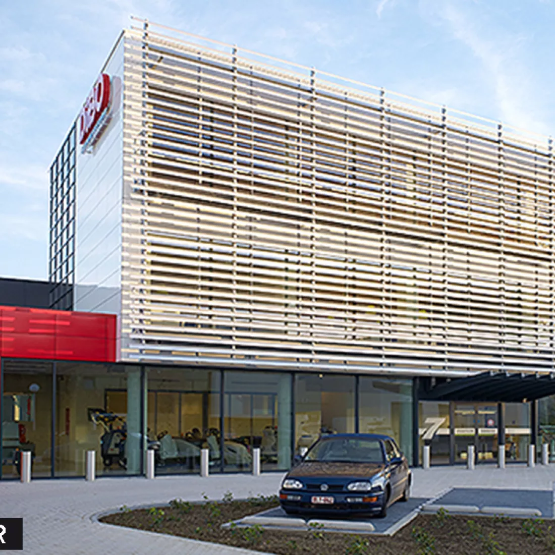 Vooraanzicht werkgebouw DIBO voor renovatie gevel. Hierbij bevat het gebouw rode tegels voor de eerste verdieping en de andere verdiepingen witte tegels.